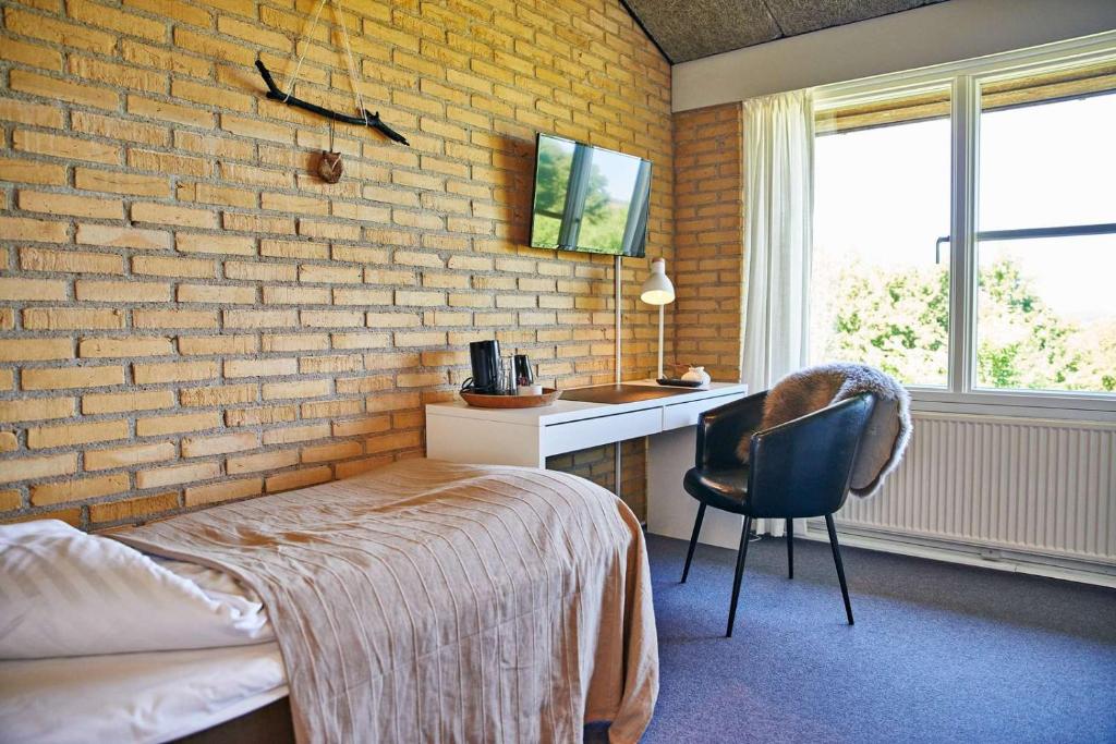 een slaapkamer met een bakstenen muur, een bed en een bureau bij Danhostel Horsens in Horsens