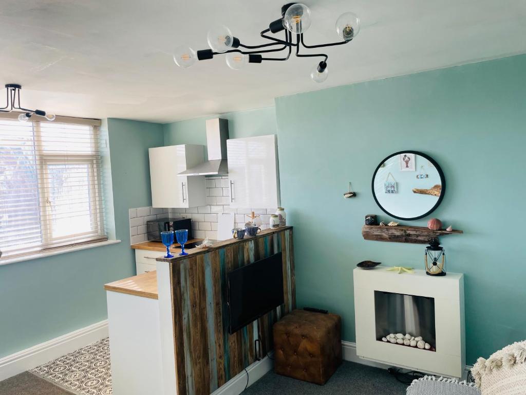 a kitchen with blue walls and a tv in a room at Seaside Loft in Lytham St Annes