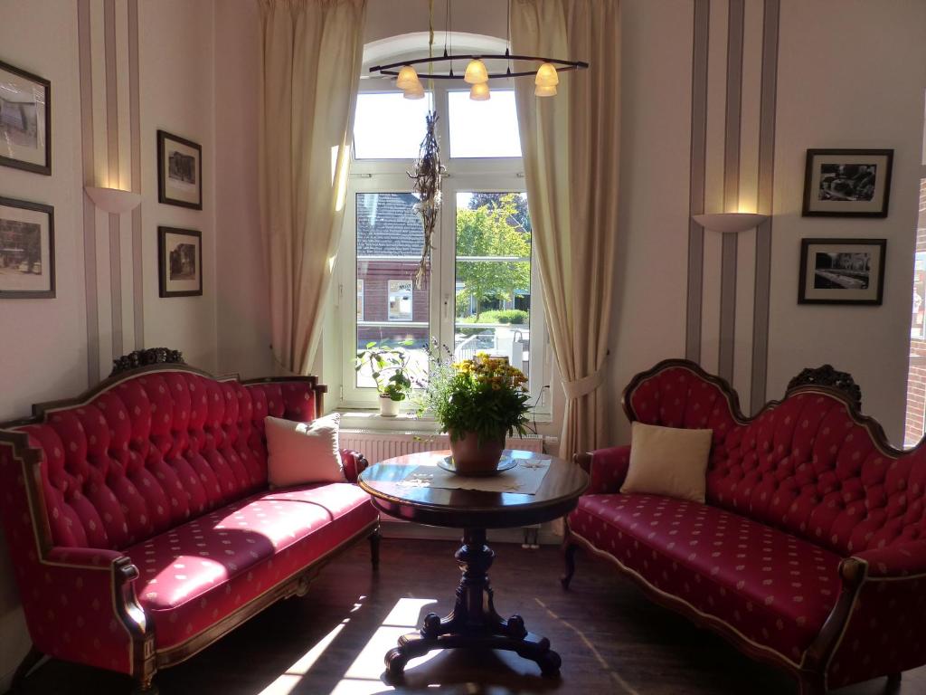 ein Wohnzimmer mit roten Sofas, einem Tisch und einem Fenster in der Unterkunft Hotel am Rathaus in Schönberg in Holstein