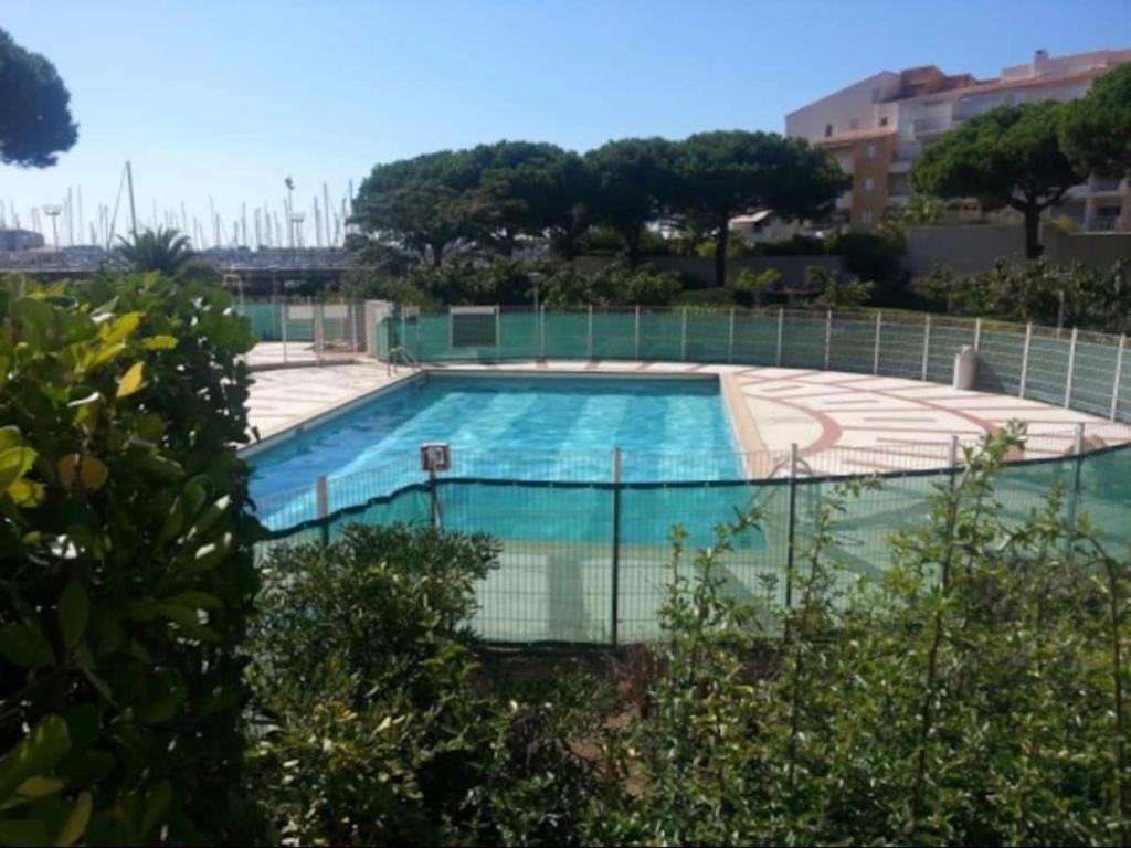 une grande piscine entourée d'une clôture. dans l'établissement Studio - piscine, proche de la plage et du port, au Cap d'Agde