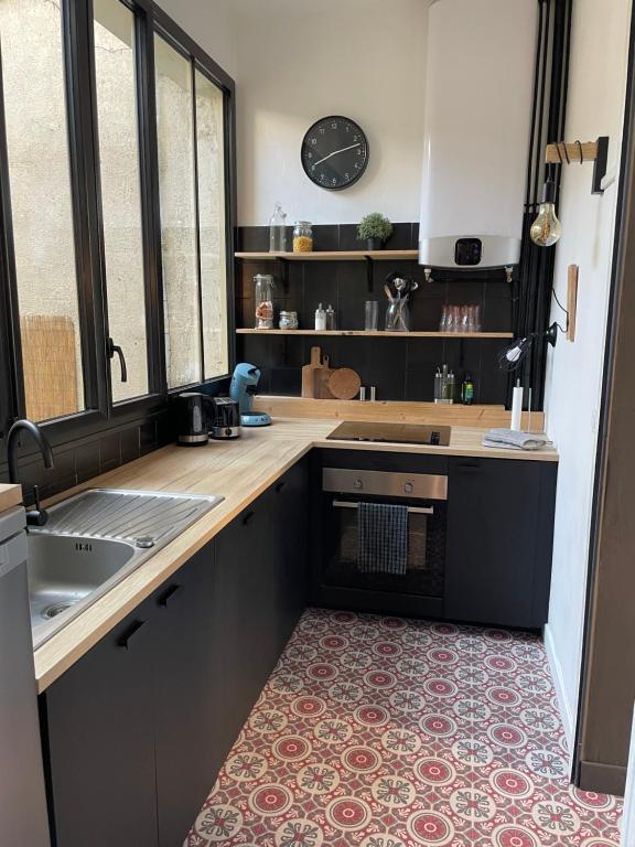 a kitchen with a counter and a sink and a clock at L industriel rémois, centre ville, proche de la cathédrale in Reims