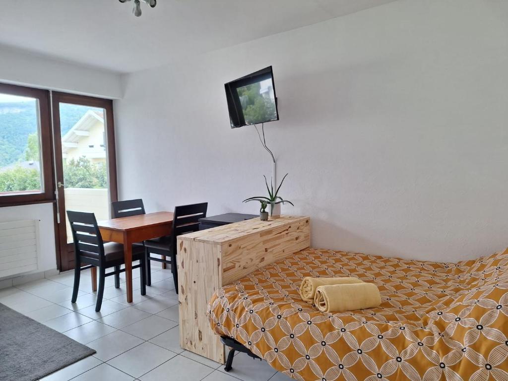 a bedroom with a bed and a table with chairs at Appartement au calme avec balcon proche Genève in Gaillard