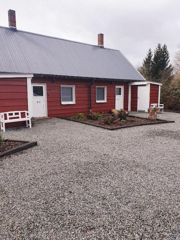 a red and white building with a gravel parking lot at Ferienhaus Svensson Altheide in Altheide