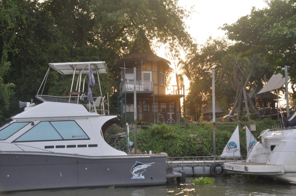 a boat docked at a dock with a house in the background at ayutthaya river camp and yacht charter 