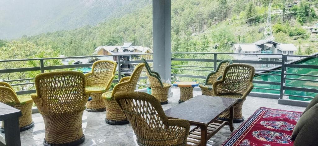 Un balcón con sillas, mesas y vistas. en Wood packers en Kasol