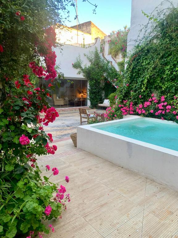 a swimming pool in a garden with pink flowers at Patios del Agua in El Puerto de Santa María