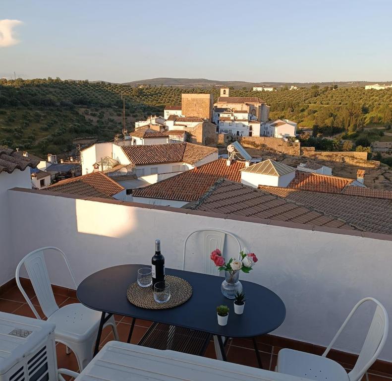 a table with a bottle of wine and flowers on a balcony at Casita Ladera, Setenil - Cádiz in Setenil