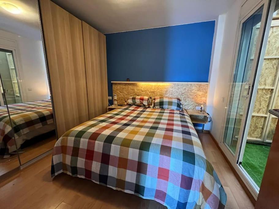 a bedroom with a bed with a plaid blanket at Acogedor piso en Terrassa in Terrassa