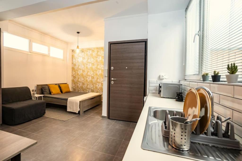 uma cozinha com um lavatório e uma sala de estar com um sofá em Urban Nest em Tessalônica