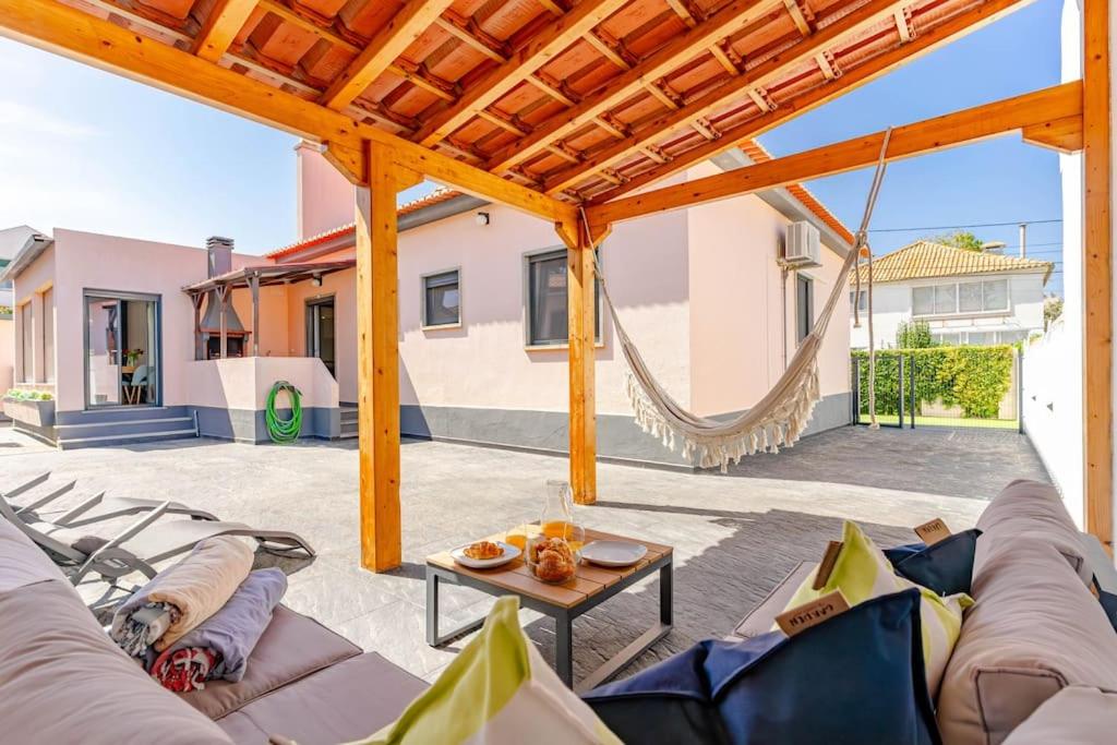 eine Terrasse mit einem Sofa, einem Tisch und einer Hängematte in der Unterkunft Caparica Dream Vila in Costa da Caparica