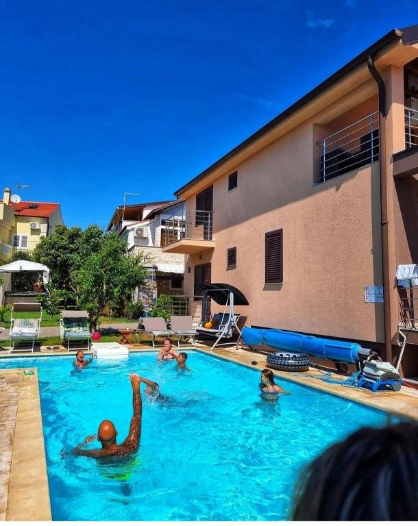 a group of people swimming in a swimming pool at Kuća NIKA in Tribunj