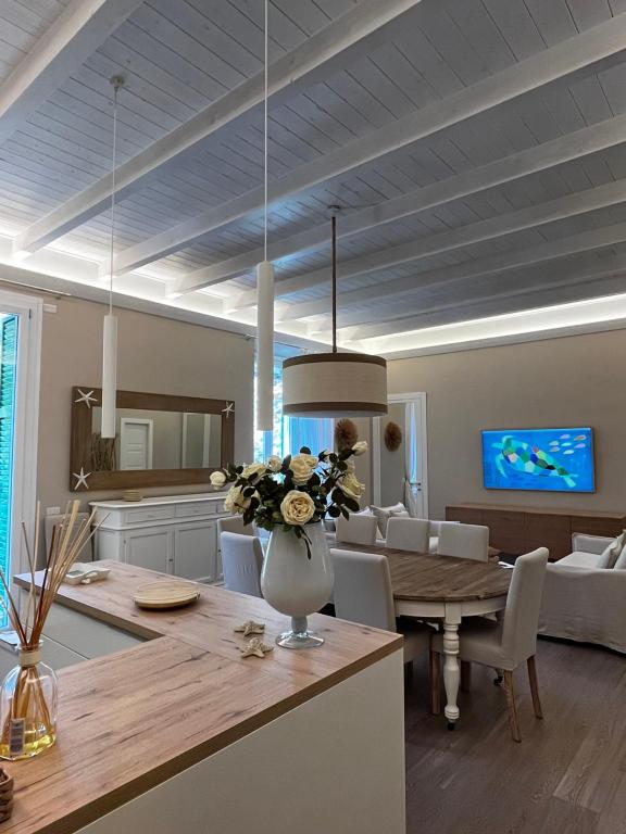 cocina y sala de estar con un jarrón de flores sobre una mesa en Luxury home Le Sirene, en Anzio