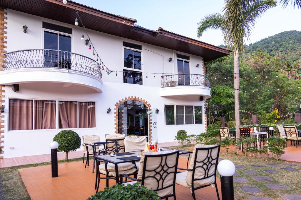 un patio con mesas y sillas frente a una casa en Mipiace, en Kamala Beach