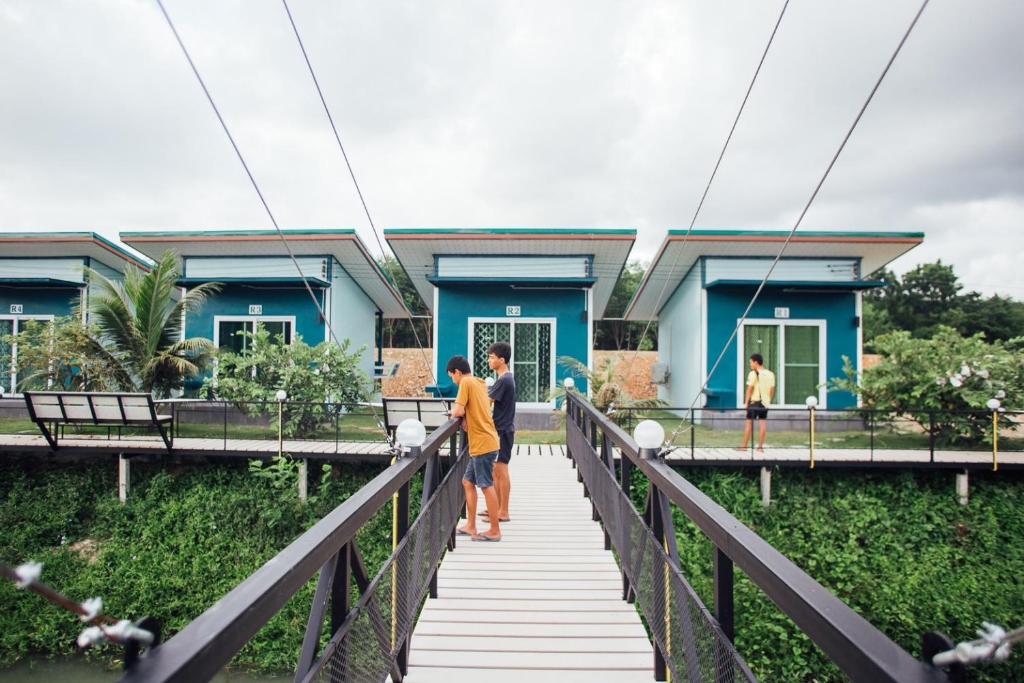 Ein Paar steht auf einer Brücke vor einem Haus. in der Unterkunft Green Country Park Resort in Ban Tha Mak