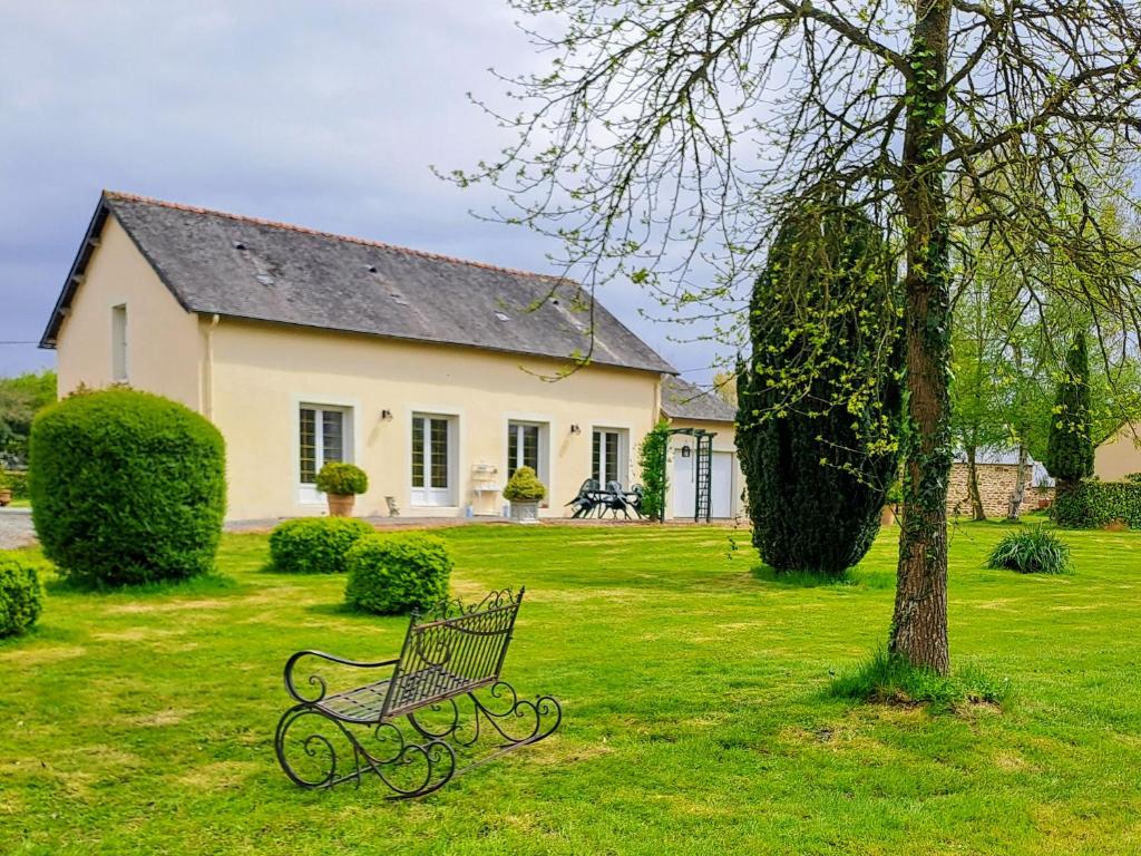 a bench sitting in the grass in front of a house at gîte de bon air in Sens-de-Bretagne