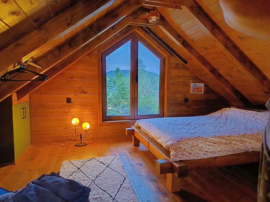 um quarto no sótão com 2 camas e uma grande janela em Brvnara Beli em Gornji Milanovac