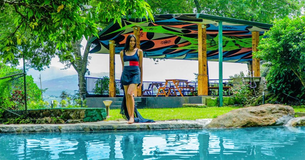 a woman standing next to a swimming pool at Siyonra Bungalow in Matale
