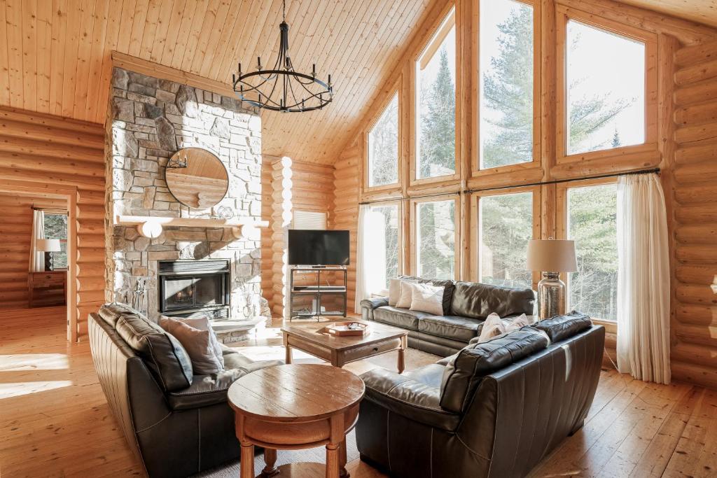 ein Wohnzimmer mit Ledermöbeln und einem Steinkamin in der Unterkunft Fiddler Lake Resort Chalet 47 Deer in Mille-Isles
