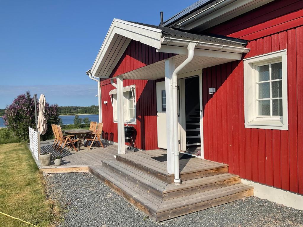 Casa roja con terraza de madera y mesa en Villa med sjöutsikt, en Fors
