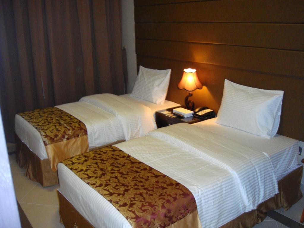 a hotel room with two beds and a table with a lamp at Paragon Hotel Apartments in Abu Dhabi