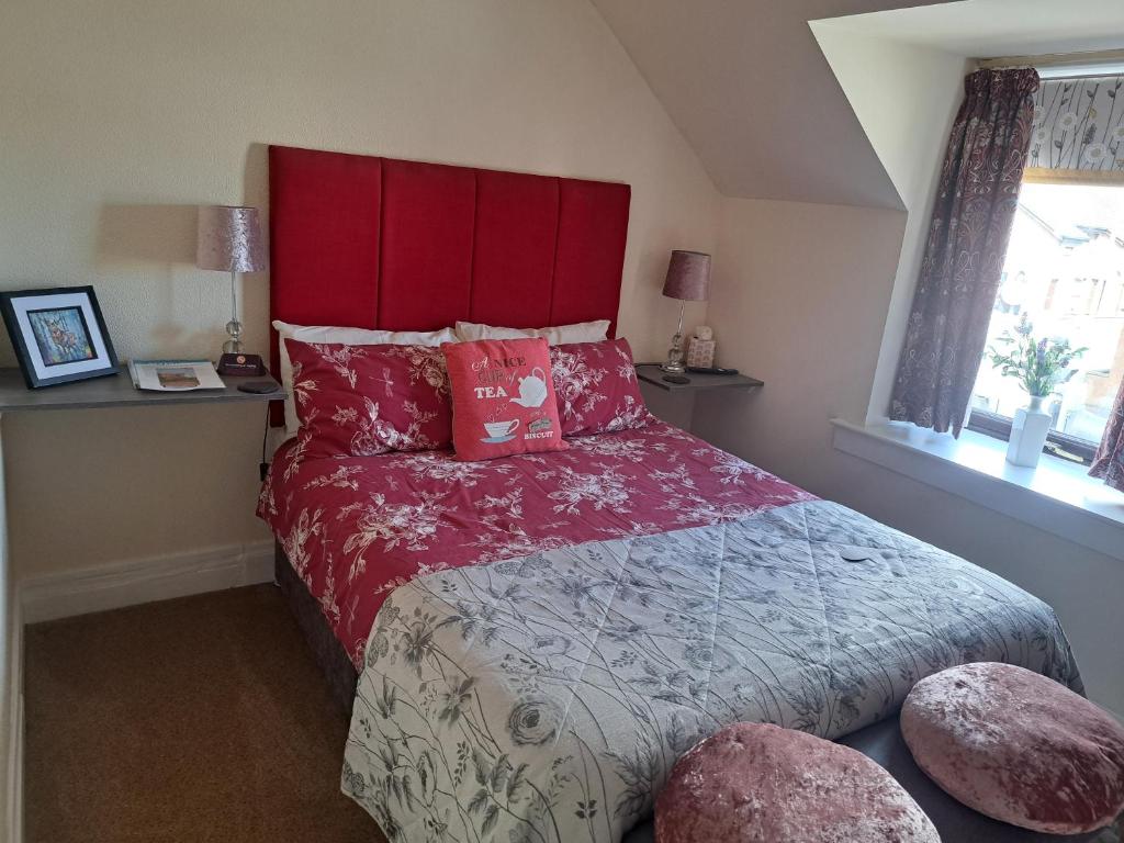 um quarto com uma cama grande e uma cabeceira vermelha em No 27 em Inverness