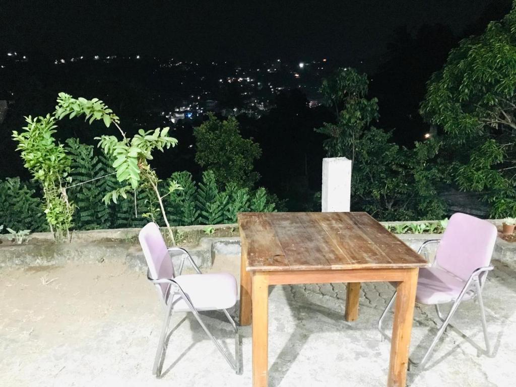 een houten tafel en 2 stoelen op een patio bij WHITE ROSE VILLA in Kandy