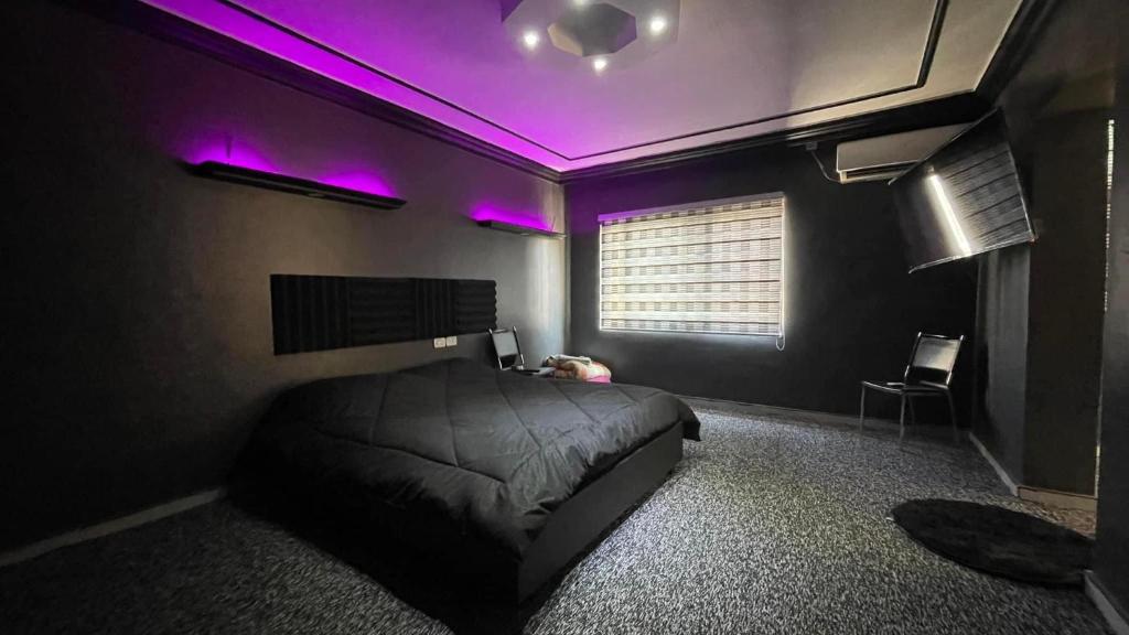 1 dormitorio con luces moradas en el techo en aljazeera apartments, en Amán
