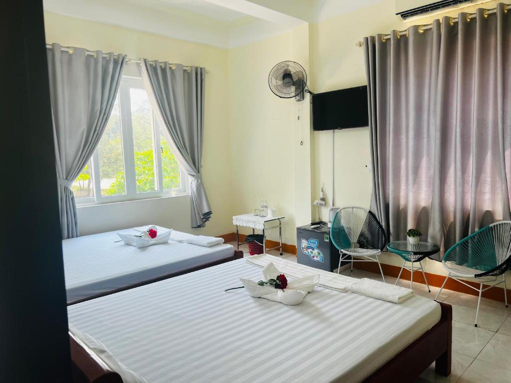 two beds in a room with two windows at View Nhat Le Beach Hotel in Dong Hoi