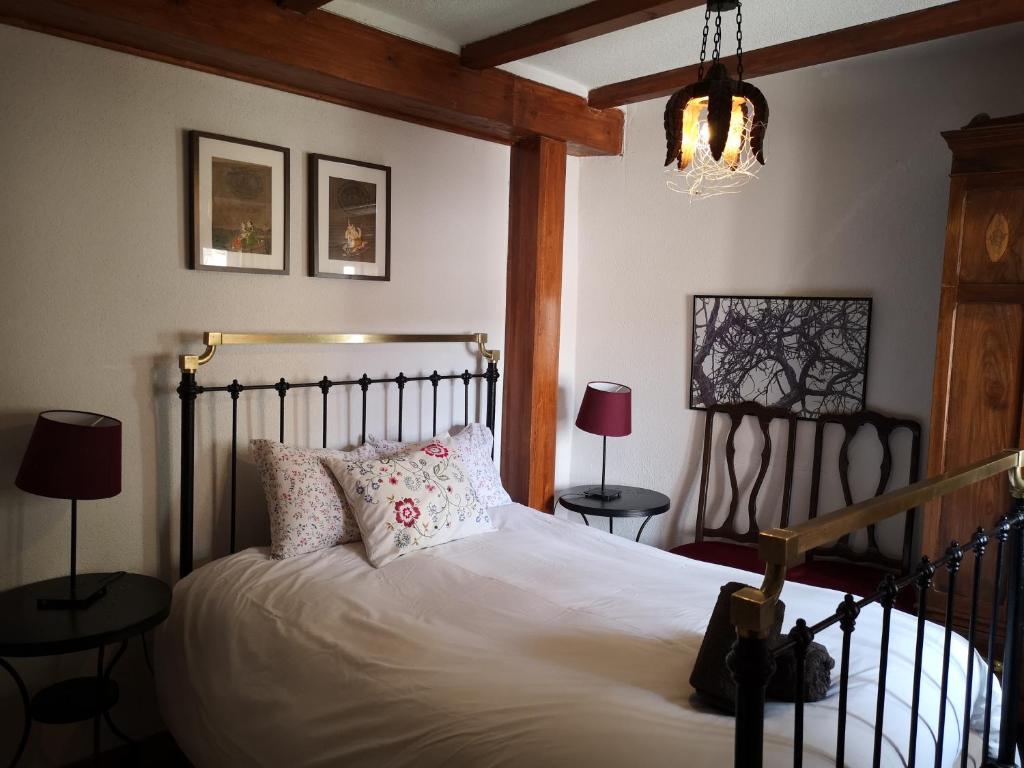 1 dormitorio con 1 cama con sábanas y almohadas blancas en La Casa Roja del Alto Tajo en Ablanque