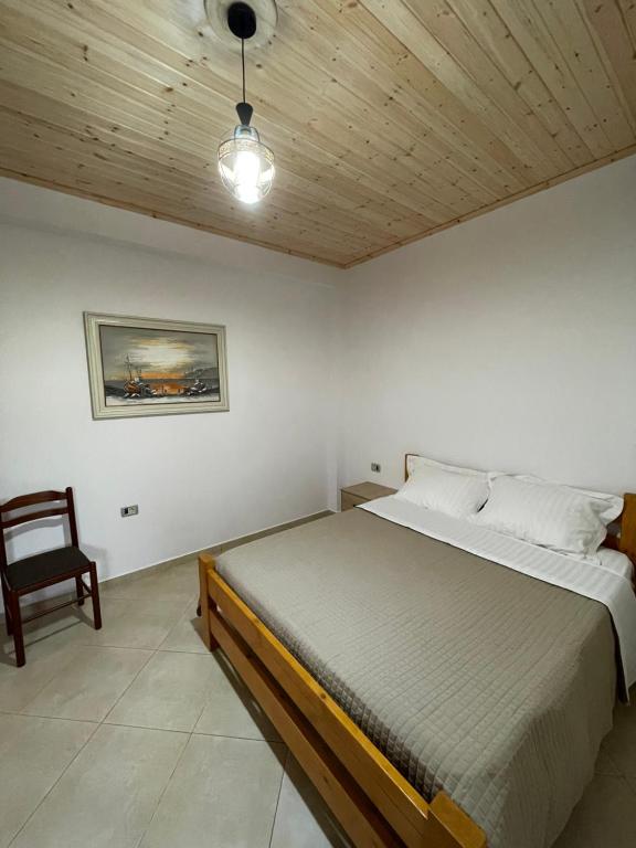 a bedroom with a large bed and a chair at Rent Rooms Sakolli in Berat