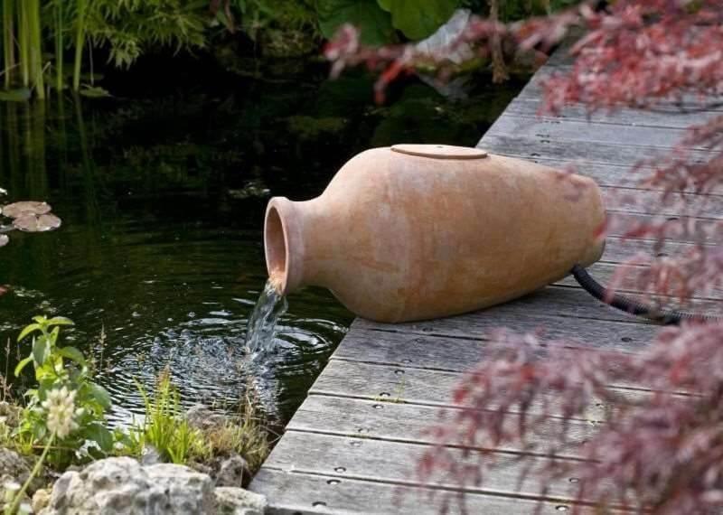 um jarro sentado ao lado de um lago com uma fonte de água em Appartamento Terme Relax em Montegrotto Terme