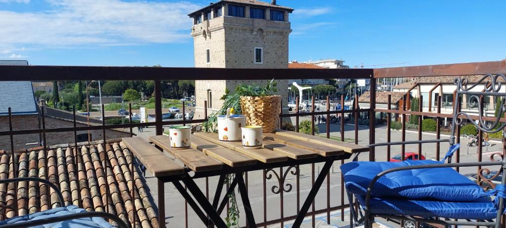 a wooden table and chairs on a balcony with a tower at Dalla Torre al mare in Cervia