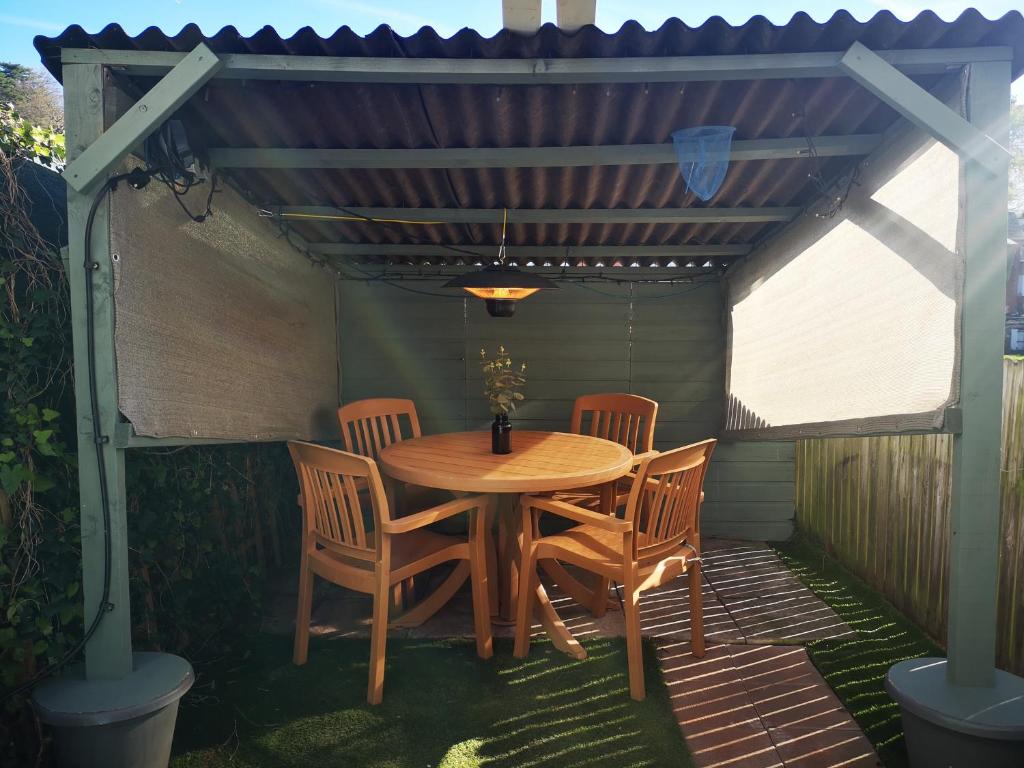 une table et des chaises en bois sous une pergola dans l'établissement Hideaway, à Torquay