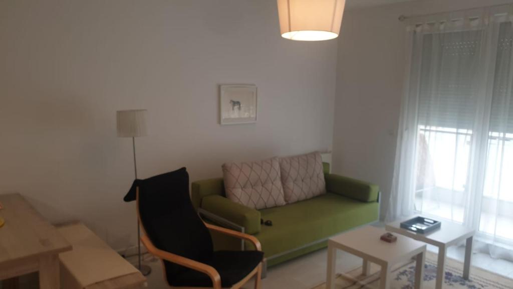 sala de estar con sofá verde y mesa en White Apartments, en Pristina