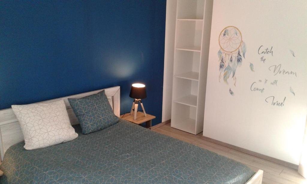 Schlafzimmer mit einem Bett mit blauer Wand in der Unterkunft Aux 3 épis in Dienville