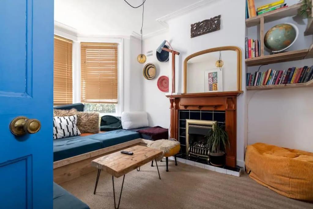 a living room with a blue couch and a fireplace at Boho Hideaway in Lea Bridge in London