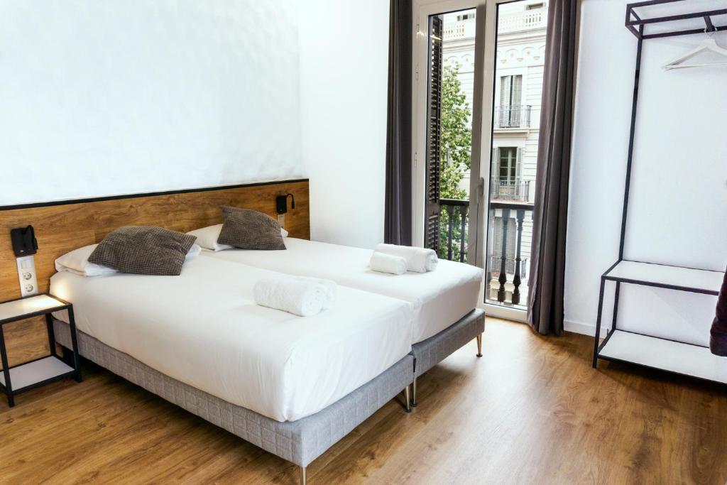 a bedroom with a white bed and a large window at Fontanella Green House in Barcelona