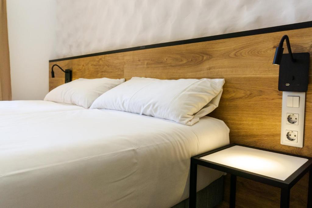 a bedroom with a white bed with a wooden headboard at Fontanella Green House in Barcelona