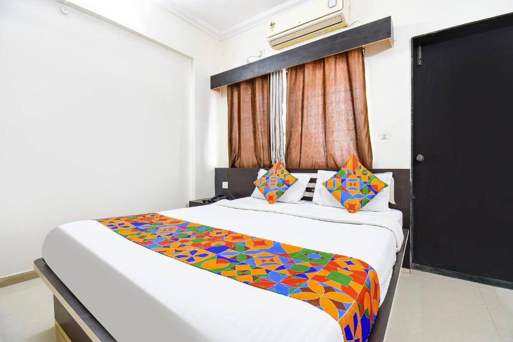 a bedroom with a large bed with a colorful blanket at FabHotel Yashraj Inn in Vagholi