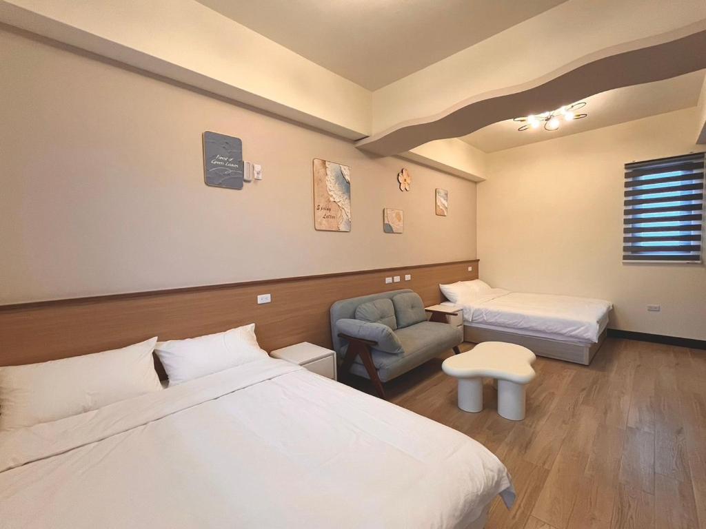 馬公市にある夜宿水巷民宿のベッド2台と椅子があるホテルの部屋