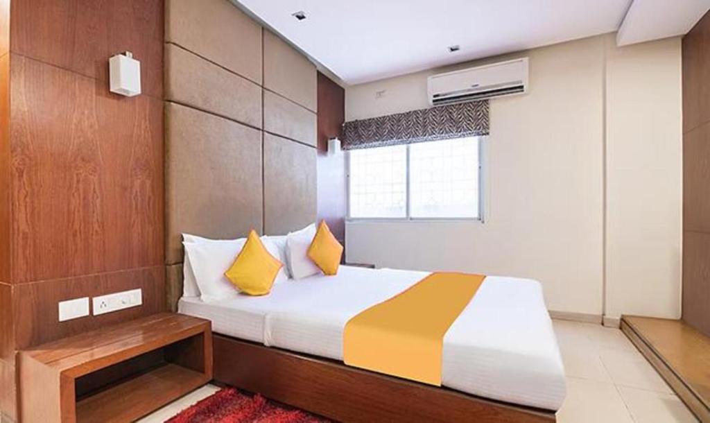 ein Schlafzimmer mit einem Bett mit gelben Kissen und einem Fenster in der Unterkunft FabExpress The Kings 10 Laxurious in Bangalore