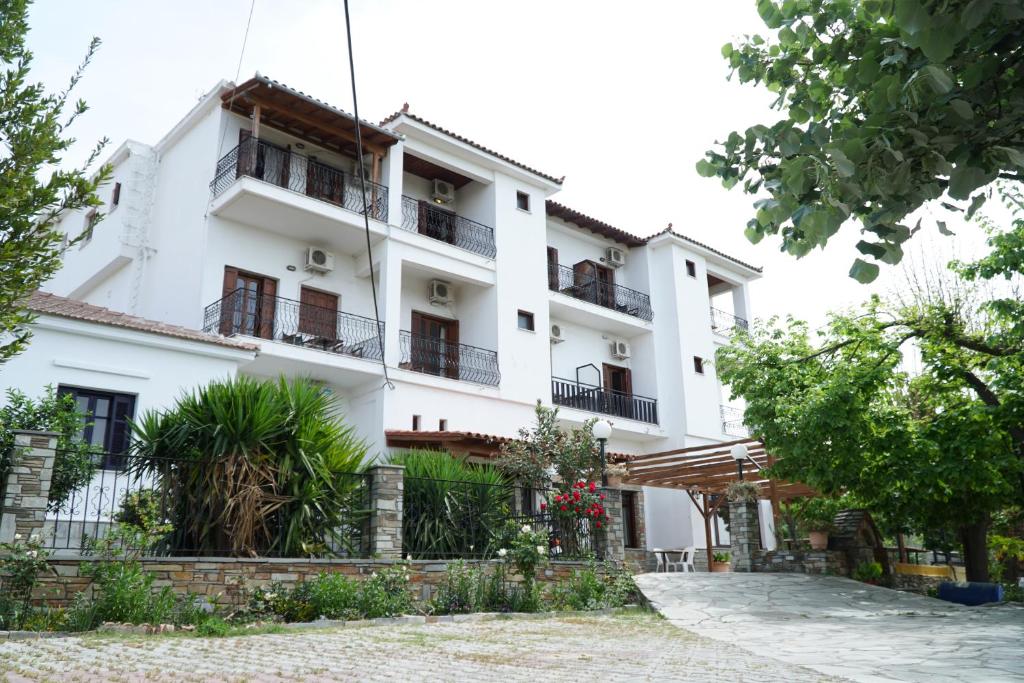 a white building with balconies and trees at Hotel Defkalion in Álli Meriá