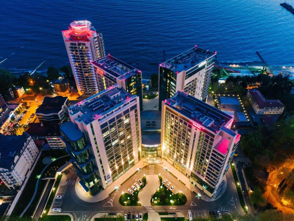 een groep van hoge gebouwen in een stad 's nachts bij Mercure Sochi Centre Hotel in Sotsji