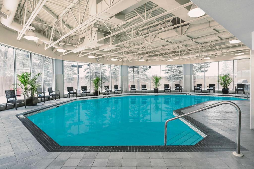 einen Pool in einer Hotellobby mit Tischen und Stühlen in der Unterkunft Hilton Garden Inn Calgary Airport in Calgary