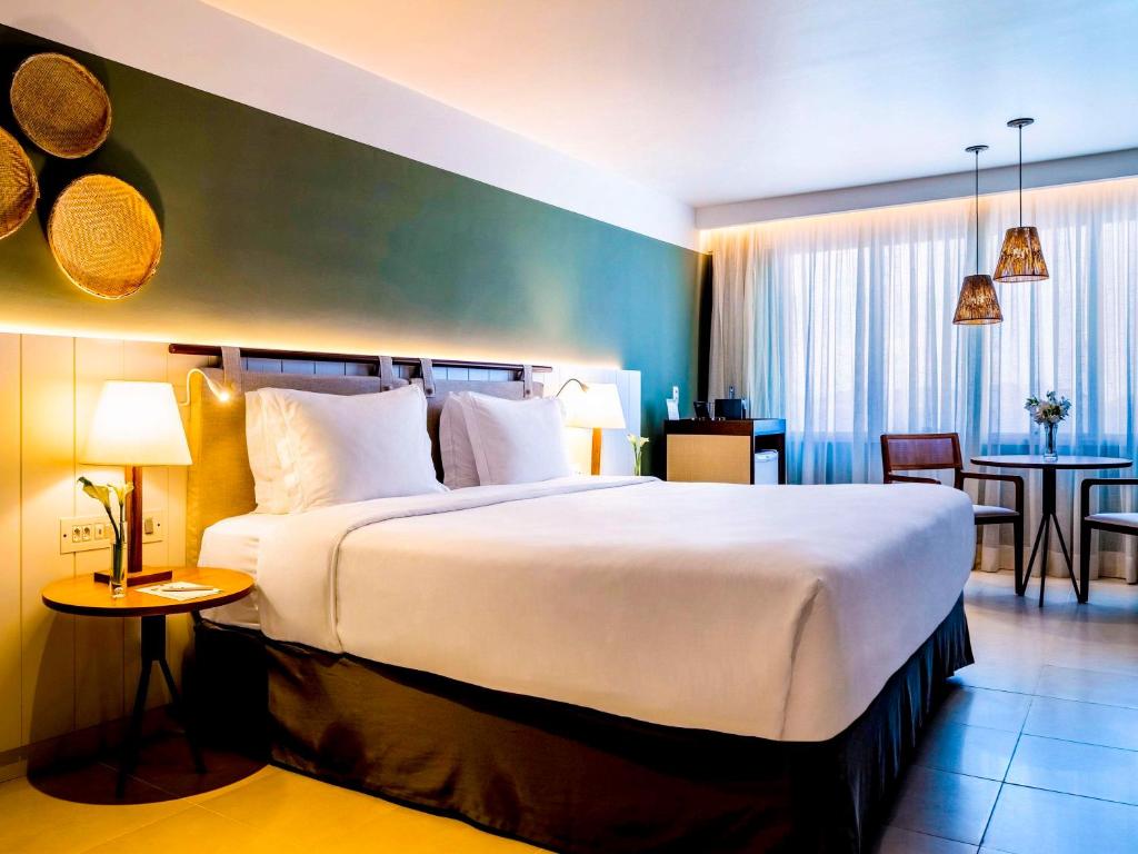 a hotel room with a large bed and a dining room at Grand Mercure Rio de Janeiro Copacabana in Rio de Janeiro