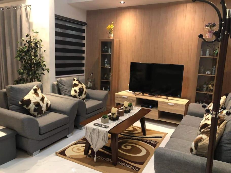 uma sala de estar com sofás e uma televisão de ecrã plano em 3-Bedroom bungalow in San Fernando Pampanga em San Fernando