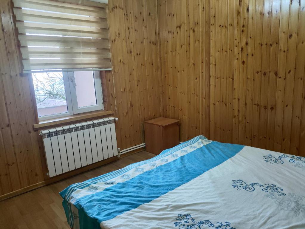 BasqalにあるBasqal Village Cottages & Restaurantのベッドルーム1室(木製の壁と窓のあるベッド1台付)