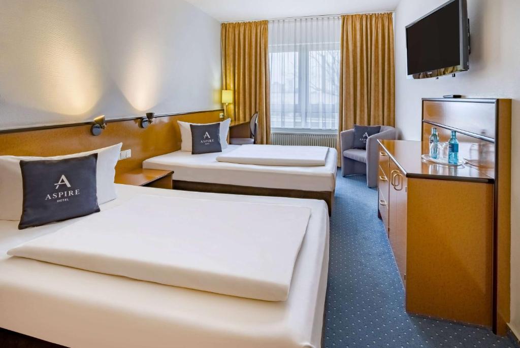 a hotel room with two beds and a television at Aspire Frankfurt Airport, Trademark Collection by Wyndham in Rüsselsheim