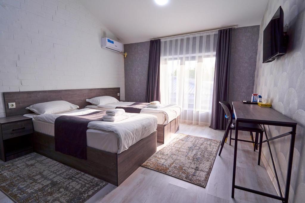- une chambre avec 2 lits, un bureau et une fenêtre dans l'établissement Minguzar Hotel, à Tachkent