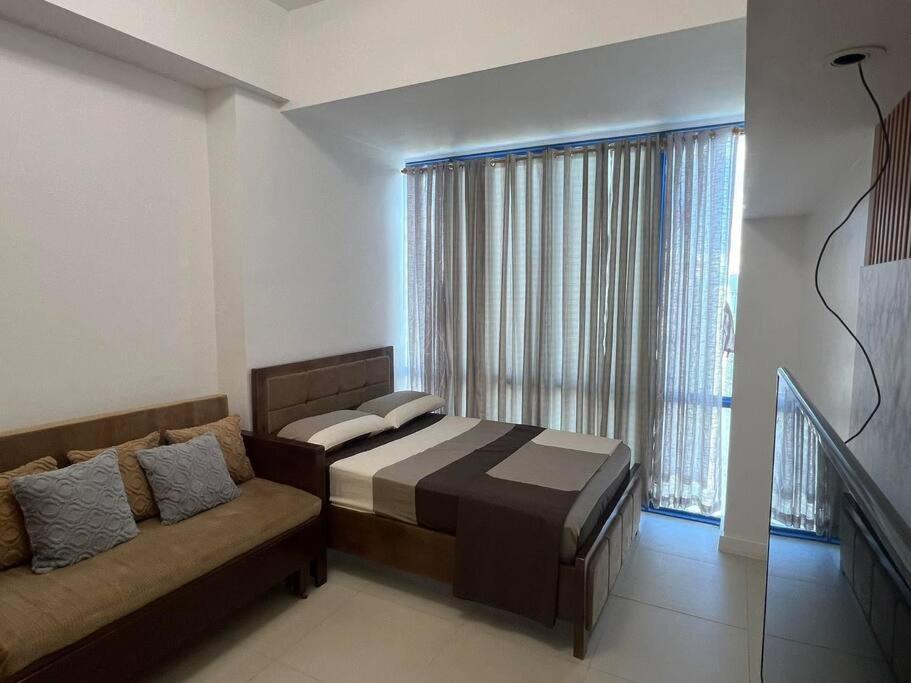 - une chambre avec un lit, un canapé et une fenêtre dans l'établissement Studio Unit located at 38 Park Avenue Condominium in IT Park Cebu, à Cebu